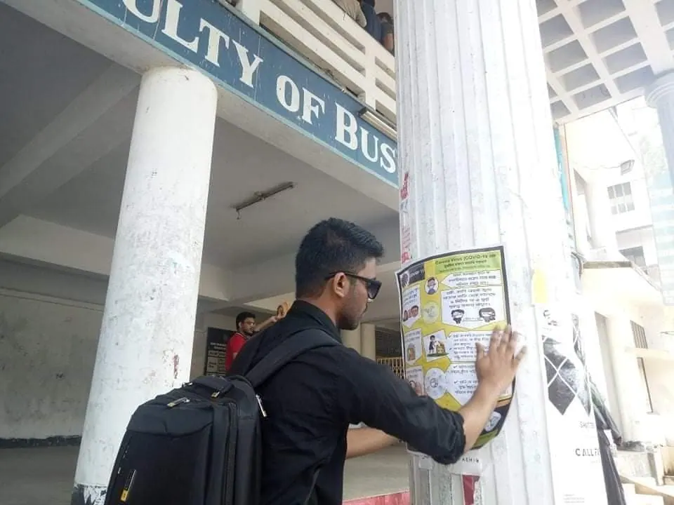 Putting up a public health awareness notice on campus.